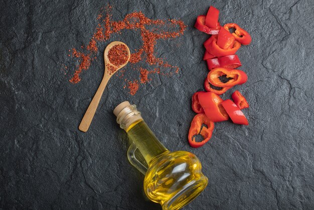 Top view of Red peppercorns with fresh red peppers slices on black background. 