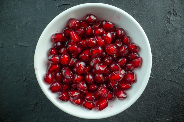 Top view red pomegranates peeled inside plate on grey surface