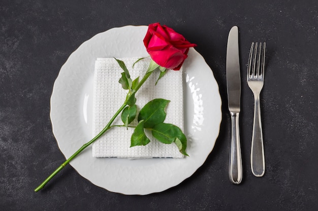 Вид сверху красная роза на тарелке со столовыми приборами