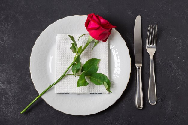 Top view red rose on a plate with cutlery