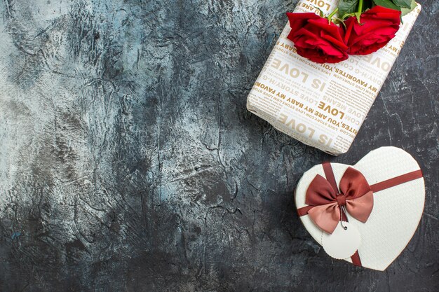 Top view of red roses and beautiful gift boxes on icy dark background with free space