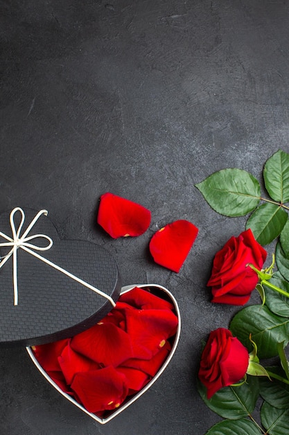 Top view red roses with box full of rose petals for valentines day on dark background love heart couple color passion feeling