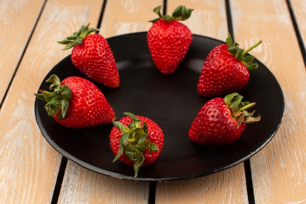 top view red strawberries fresh mellow whole inside black plate on the wooden floor