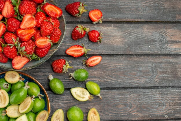 Top view red strawberries with fresh feijoas on dark wooden rustic desk