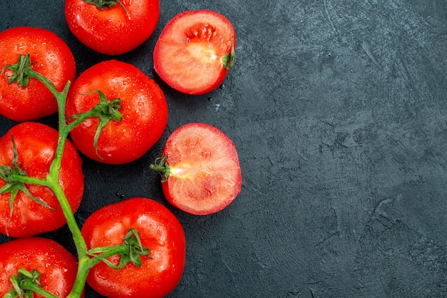 Top view red tomato branch tomatoes cut in half on black table with free space