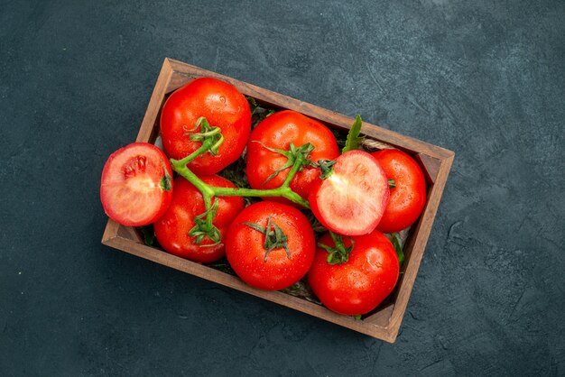 상위 뷰 빨간 토마토는 검은색 테이블 여유 공간에 있는 나무 상자에 토마토를 자른다
