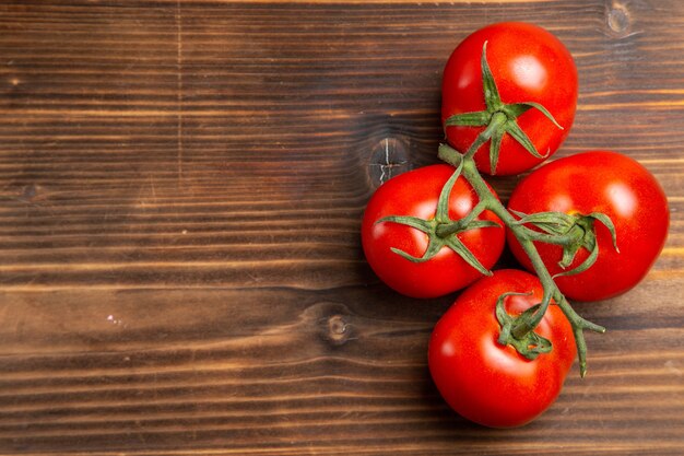 Top view red tomatoes ripe vegetables on brown wooden desk