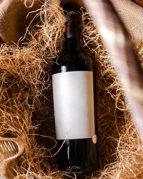 Foto gratuita una vista dall'alto bottiglia di vino rosso di vino rosso sul fieno