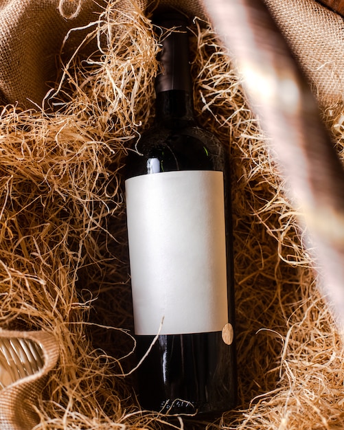 Вид сверху бутылка красного вина из красного вина на сене