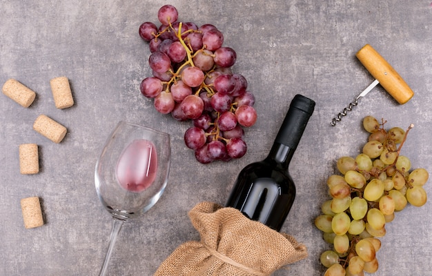 Top view red wine in sackcloth bag with glass and grape on dark stone  horizontal