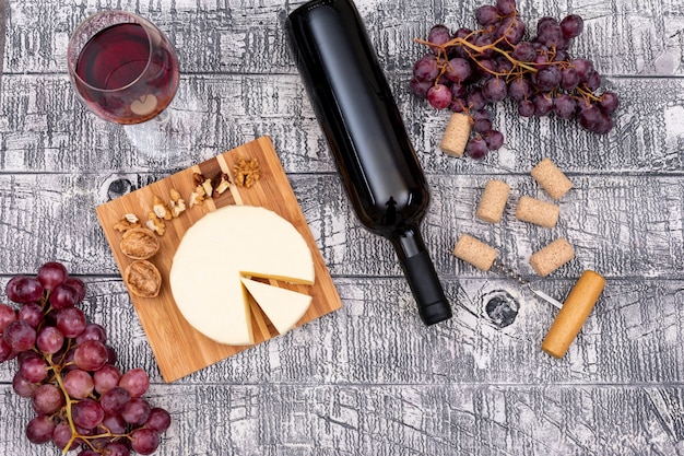 Top view red wine with grape and cheese on board and on white wooden  horizontal
