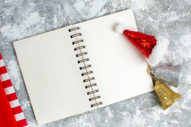 Top view red xmas toy on notebook xmas bells on grey white table