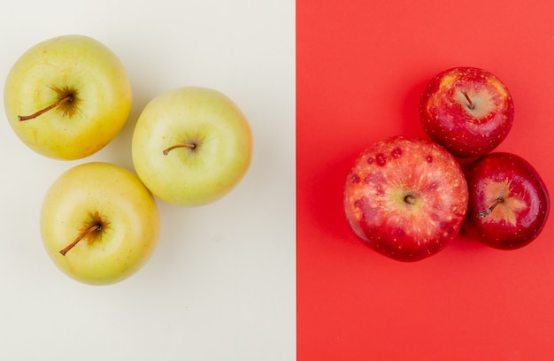 Top view of red and yellow apples on ivory and red background