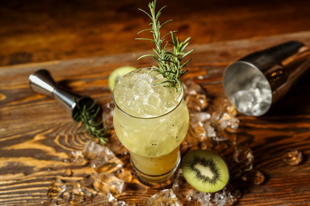 Top view refreshing cocktail with rosemary and kiwi on ice on the table