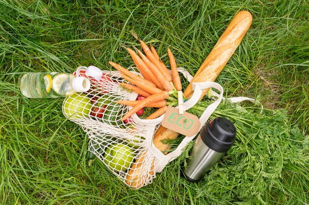 Top view reusable bag with groceries on grass