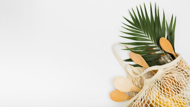 Top view of reusable bag with wooden spoons and leaf