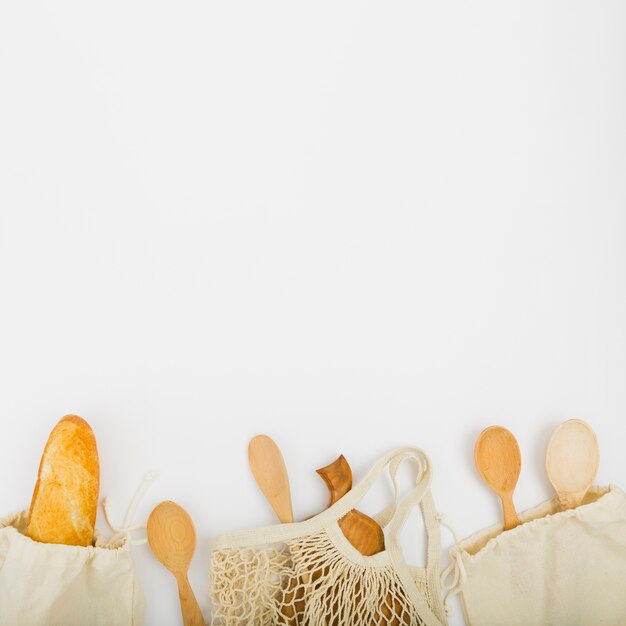 top view of reusable bags with bread and wooden spoons