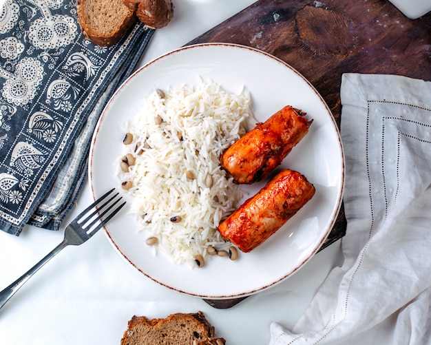 Рис сверху с фасолью и жареным мясом внутри белой тарелке на светлом полу