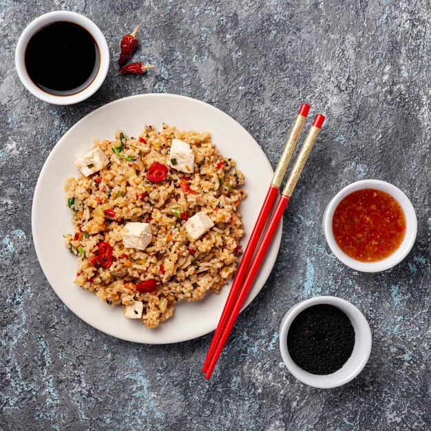 Top view rice with vegetables soy sauce and chopsticks