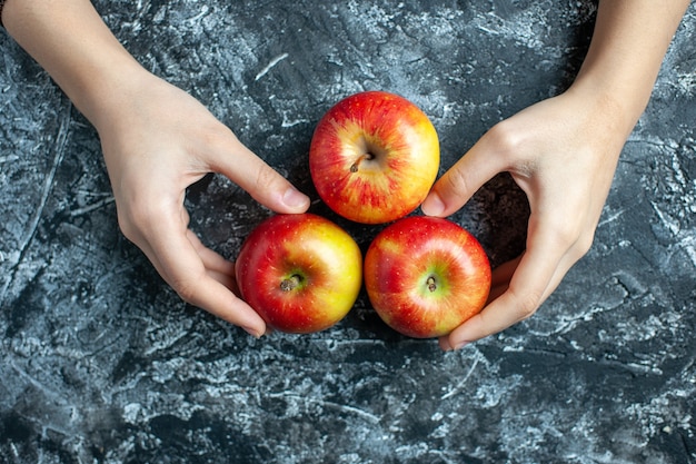 Free photo top view ripe apples female hands on grey background with copy place