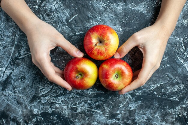 コピー場所と灰色の背景に女性の手で熟したリンゴの上面図