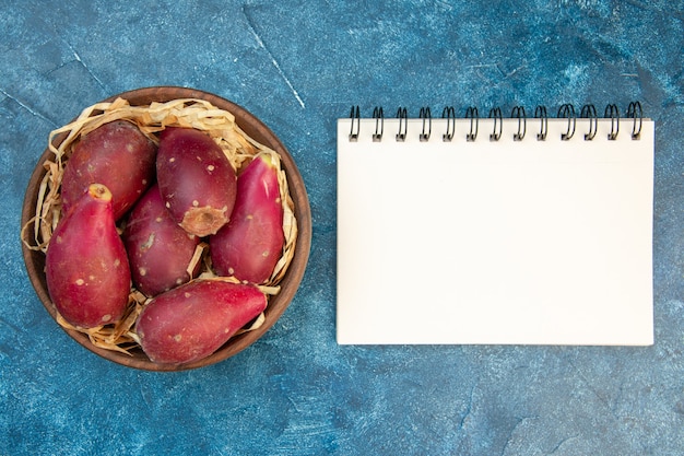 Top view ripe fresh plums inside plate on blue table