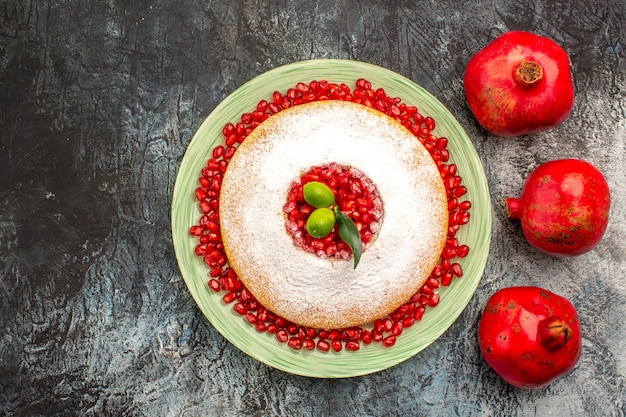 Top view ripe pomegranates ripe red pomegranates next to the plate of cake