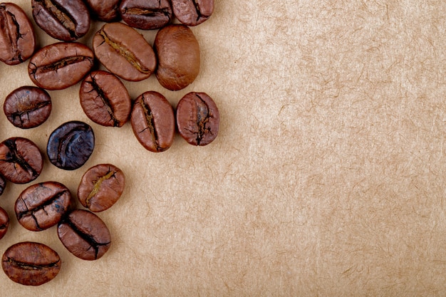 Free photo top view of roasted coffee beans isolated brown paper texture background with copy space