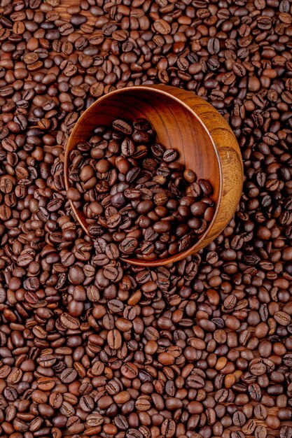 Top view of roasted coffee beans scattered from wooden bowl