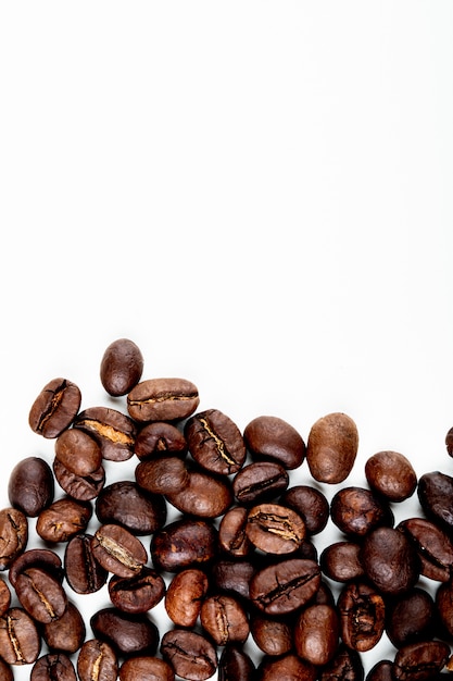 Top view of roasted coffee beans scattered on white background with copy space
