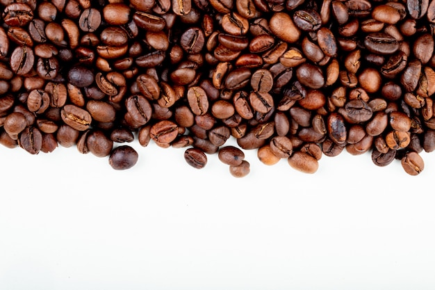 Top view of roasted coffee beans scattered on white background with copy space