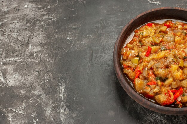 Top view of roasted eggplant salad in bowl on dark surface