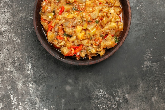 Top view of roasted eggplant salad in bowl on dark surface