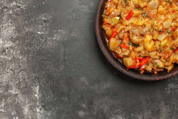 Top view of roasted eggplant salad in bowl on dark surface