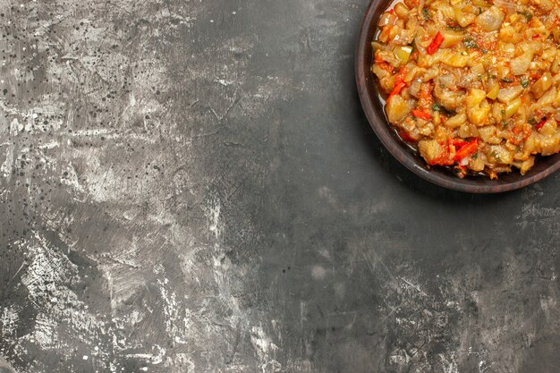 Top view of roasted eggplant salad in bowl on dark surface