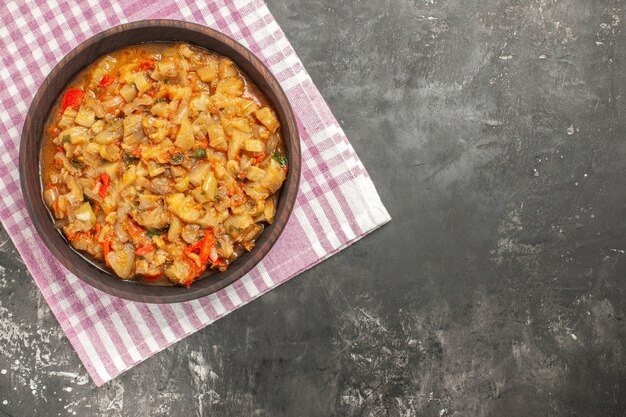 Foto gratuita vista dall'alto di insalata di melanzane arrosto in una ciotola sul tovagliolo a scacchi bianco rosa sulla superficie scura