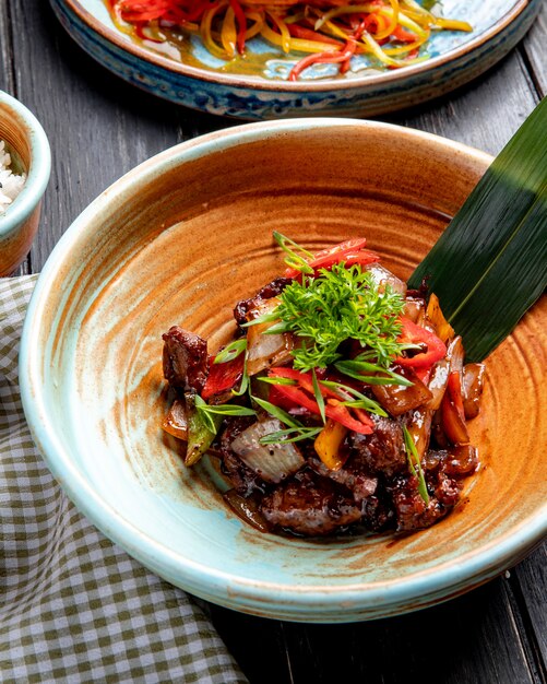 Top view of roasted lamb with vegetables and fresh herbs and sauce on a plate on wood