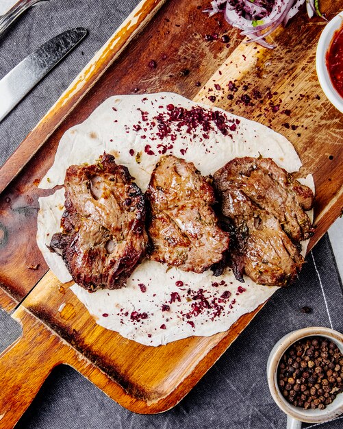 Top view of roasted meat pieces on a wooden board