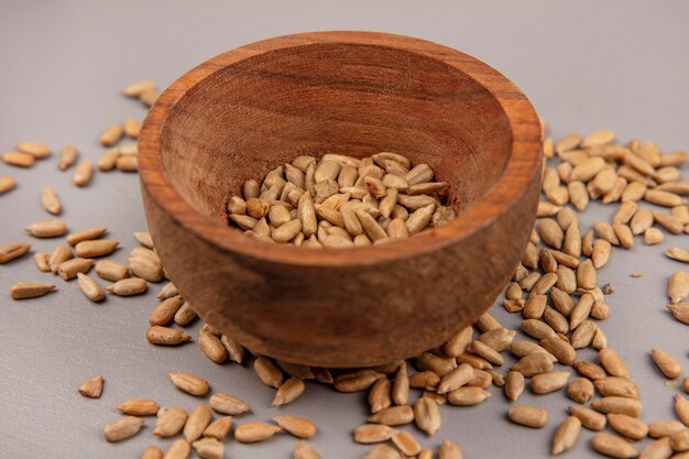 Top view of roasted shelled sunflower seeds on a wooden bowl with shelled seeds isolated