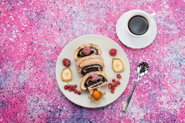 Вид сверху рулонных кусочков торта с разными фруктами внутри белой тарелки вместе с чашкой кофе на цветном фоне бисквитного торта сладкого цвета
