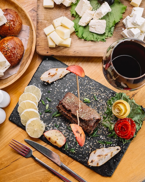 Top view roll meat with lemon slices and a glass of red wine