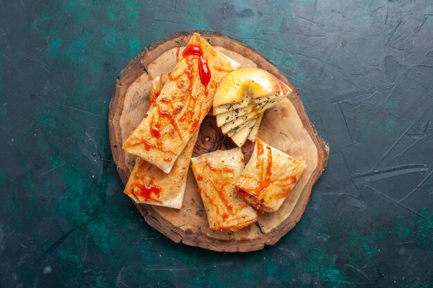 Top view rolled dough pita sliced with meat filling and sauce on dark blue desk