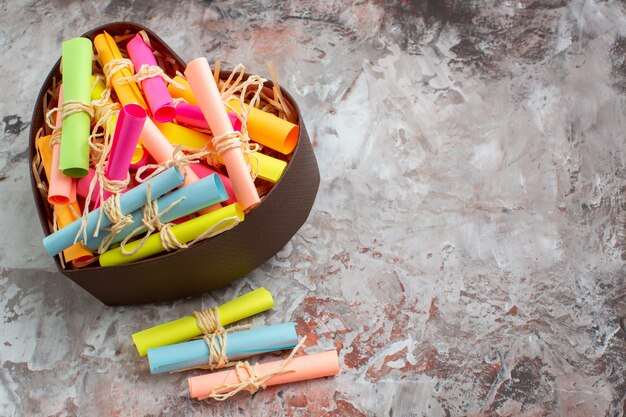 Top view rolled up colored sticky notes in heart shaped box on brown table with free space