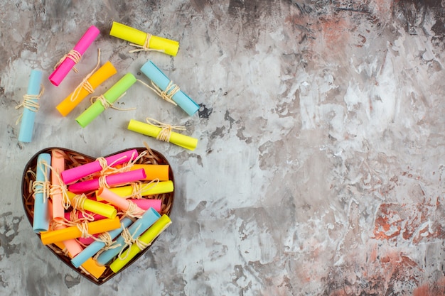 Top view rolled up colored sticky notes in heart shaped box on table with free space