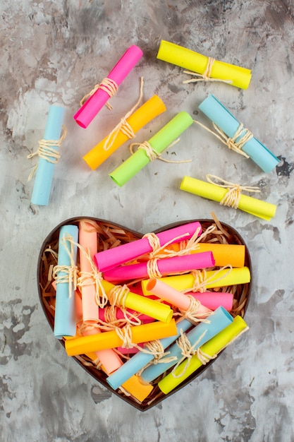 Top view rolled up colored sticky notes in heart shaped box on table