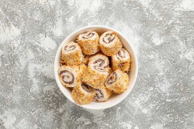 Top view rolls candies sweet confitures inside plate on white background