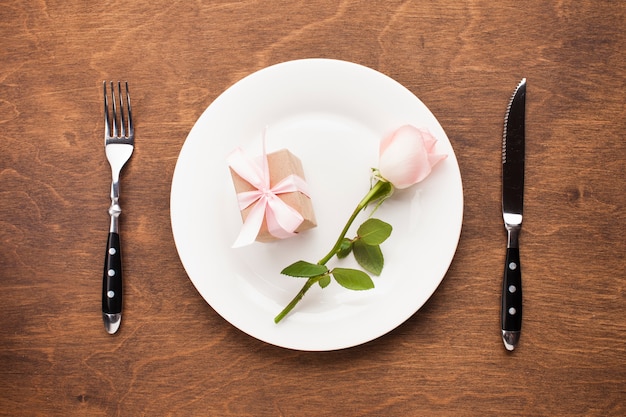 Free photo top view rose and gift on a plate