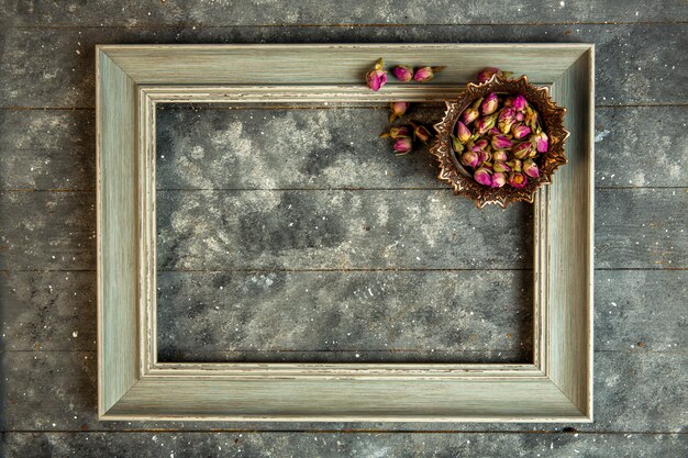 top view rose tea in bowl and a wooden empty frame