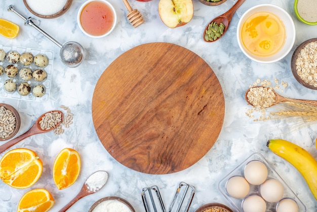 Top view of round board and ingredients for the healthy food set on stained white background