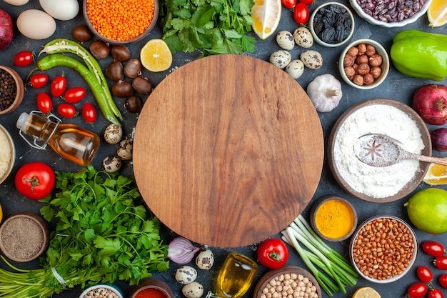 Top view round dough board beans in bowl garlic lemon tomato hazelnut pomegranate parsley on table